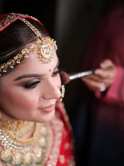 Another angle of our artist at work, ensuring every detail of the bride's makeup is perfect. We take pride in our meticulous application, which guarantees a long-lasting and photogenic finish.