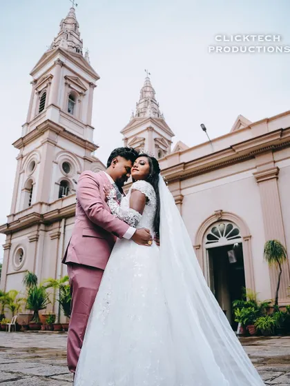 A wide shot showing the full length of the bride's gown and veil as she embraces her husband.