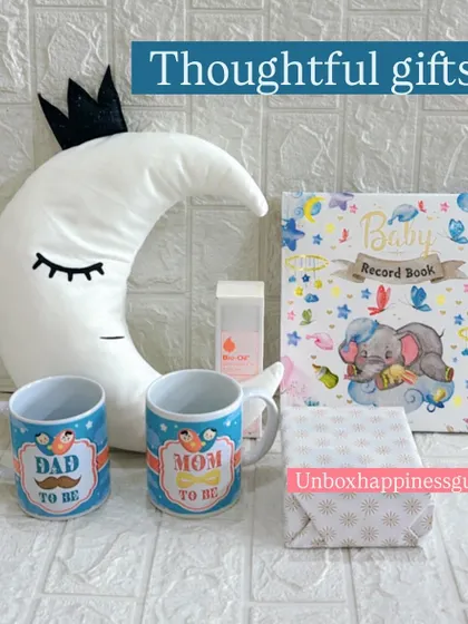The contents of the moon-themed hamper displayed individually. This set includes "Dad to be" and "Mom to be" mugs, a baby record book, Bio-Oil, a soft cushion, and a wrapped gift.