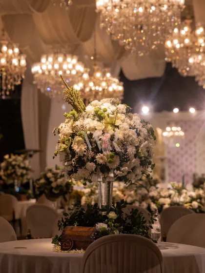 Another beautiful shot of a floral centerpiece, with its layers of white flowers and greenery. The out-of-focus background filled with chandeliers emphasizes the scale and opulence of the event.