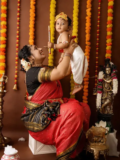 A joyful mother lifts her baby Krishna, who holds his flute high.