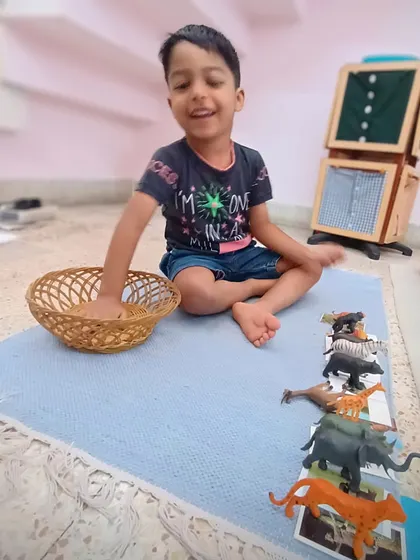 This child is matching animal figures to their corresponding pictures. This is a key pre-reading activity that builds vocabulary, develops classification skills, and strengthens the child's ability to make connections between objects and their representations.