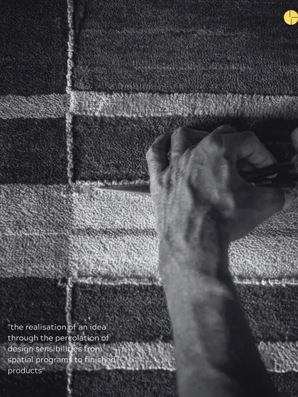 A black and white photo capturing the intense focus of a craftsman's hand at work on one of the Elemental rugs.