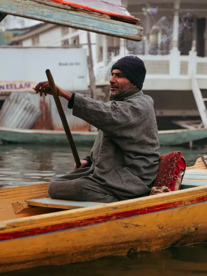 Another portrait of a Kashmiri boatman, taking a moment to smoke. His weathered face and the serene backdrop tell a thousand stories.