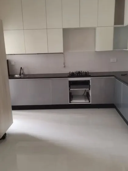A minimalist kitchen in the final stages of installation, showing a two-tone design with grey and white cabinets. The layout is designed for a clean, uncluttered look with ample storage.
