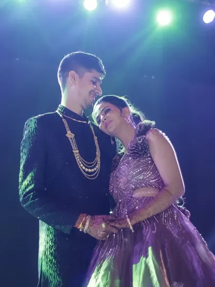 A quiet, romantic moment amidst the Sangeet celebration. The bride rests her head on the groom's shoulder as they stand on the dance floor, a pocket of peace in the middle of the party.