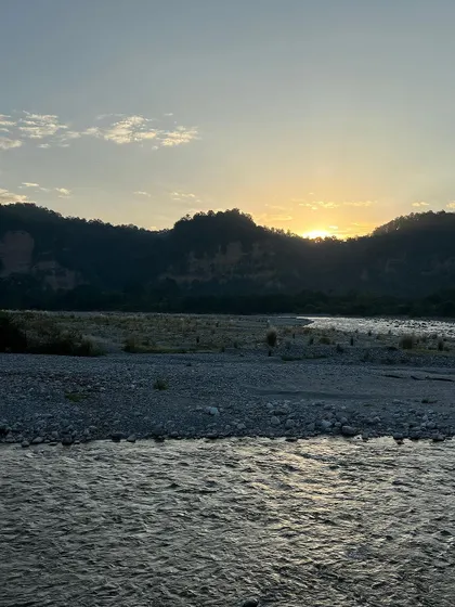 A wide view of the river valley at sunrise, with soft clouds in the sky. The landscape feels vast and peaceful as a new day begins.