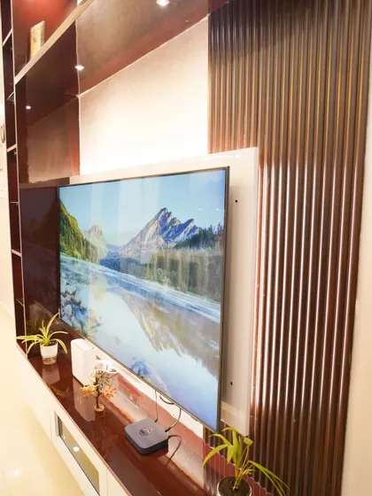 A close-up of the entertainment unit, showing the detailed fluted wood paneling and the seamless integration of the television. The design adds texture and warmth to the living space.