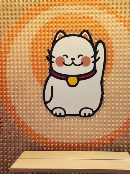 A close-up of the Maneki-neko or "lucky cat" at the center of our wooden peg mural, showing the clean lines and friendly design.