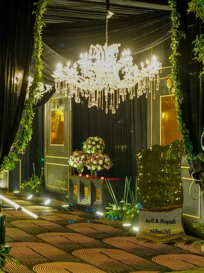 The grand entrance to a glamorous cocktail party, featuring a crystal chandelier, lush greenery, and dramatic black draping for a luxurious and moody welcome.