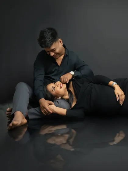 Lost in their own world. This intimate pose, with the mother-to-be lying in her partner's lap, creates a beautiful feeling of safety and connection. The reflection adds an artistic, dreamy quality.