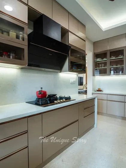 The kitchen is styled with a red kettle and colorful plates, adding a pop of personality to the neutral color scheme. The built-in hob and black chimney create a sleek and professional cooking station.
