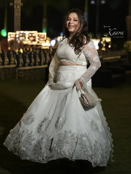 Twirling with joy. Our client in her custom white lehenga, featuring silver floral appliqué on the skirt and delicate embroidery on the sheer sleeves.