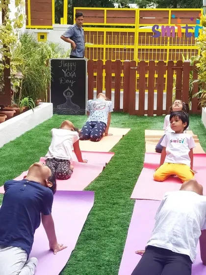 A group of children practices the camel pose, their faces turned towards the sky. This pose helps open the chest and build confidence.