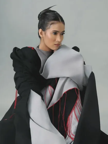 The architectural outfit is paired with a sharp, minimalist white liner and spiky hair for a cohesive, avant-garde look.