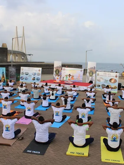 A wide shot of the Yoga Day class, showing the scale of the event and the collective energy of the community practicing together outdoors.