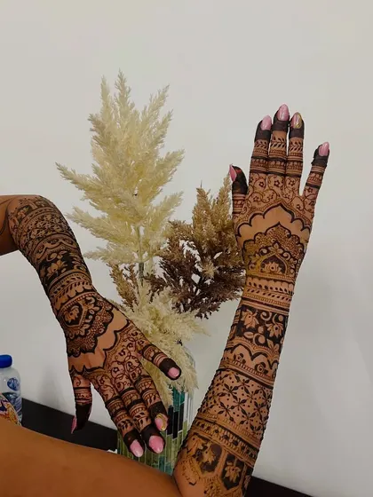 A beautiful shot of a bride showing off her full-arm mehendi, which extends from her palms to her elbows.
