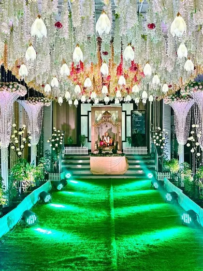 A simple and classy reception entrance. The walkway is lined with pearl-like cascades and floral pillars, leading guests toward a canopy of hanging white flowers.