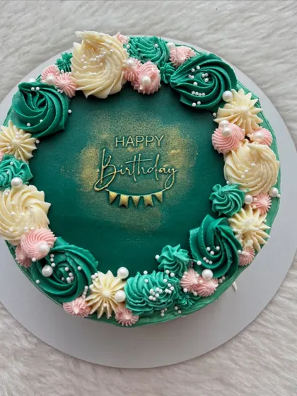 An emerald green ganache cake with beautiful piped details. The combination of green, pink, and cream frosting creates a striking and elegant color palette.