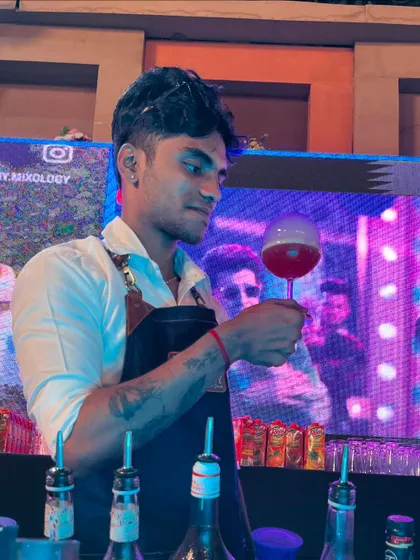 The 'Bubble Pop' cocktail held up against a dynamic, colorful background, highlighting its visual appeal in a party setting.