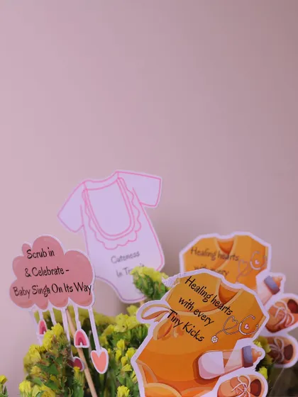 A closer look at the personalized decorative picks, featuring adorable baby-themed graphics and clever phrases that tie into the parents' profession.