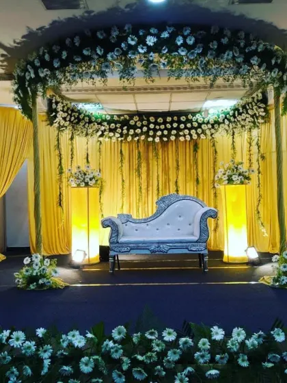 This reception decor uses a circular overhead floral structure and dramatic yellow draping to create a unique and vibrant stage design.
