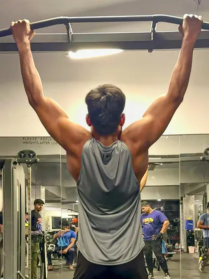 "Strong is the new sexy." A shot from below during a pull-up, highlighting the muscles of the upper back.