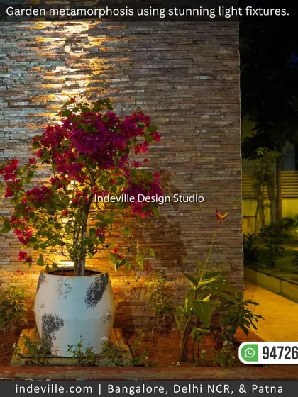 A bougainvillea plant in a rustic pot, illuminated by an uplight against a stone-clad wall. This shows how I use lighting to accentuate specific plants and textures in the garden.