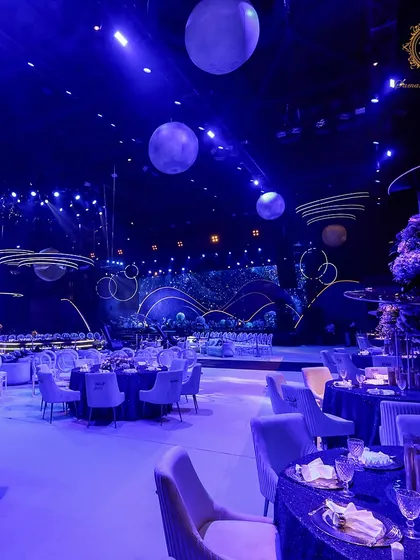Plush velvet chairs in a soft lilac color were paired with deep blue tables, with floating planet models visible in the background, continuing the celestial journey throughout the space.