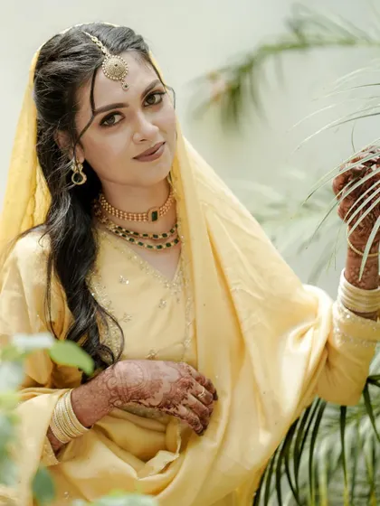 A duplicate of the bride, framed by palm leaves, looking serene and beautiful in this close-up portrait.