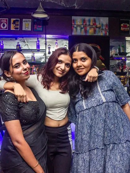 A stylish group of friends posing by the bar. The blue ambient lighting creates a cool, modern vibe for your photos.