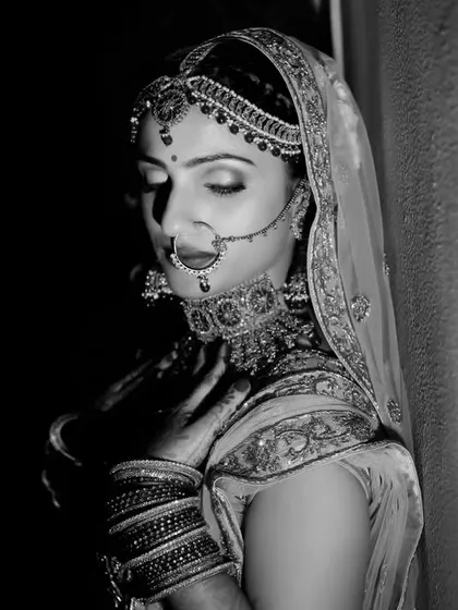 A timeless black and white portrait of a bride in a moment of quiet reflection. The dramatic lighting emphasizes her classic beauty and emotion. (Same as 47, different context)