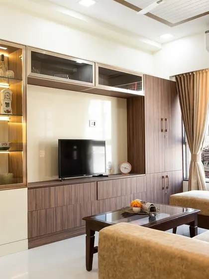 A full-wall entertainment unit in a warm wood finish, providing ample storage with a mix of open shelves and closed cabinets.