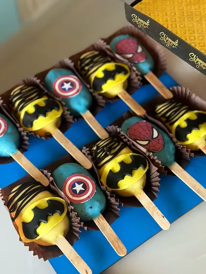 A box of our superhero cakesicles, featuring the logos of Batman, Captain America, and Spider-Man. These are a perfect party favor or addition to a dessert table.