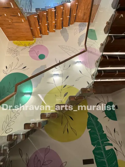 For this triple-height wall in Pondicherry, I used a boho theme with abstract color circles and delicate leaf drawings. The design enhances the minimalist, airy feel of the modern staircase.