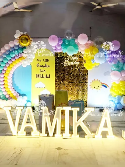 A vibrant rainbow and sunshine themed stage with large marquee letters, a sequin wall, and a beautiful balloon rainbow, creating a cheerful and happy atmosphere.