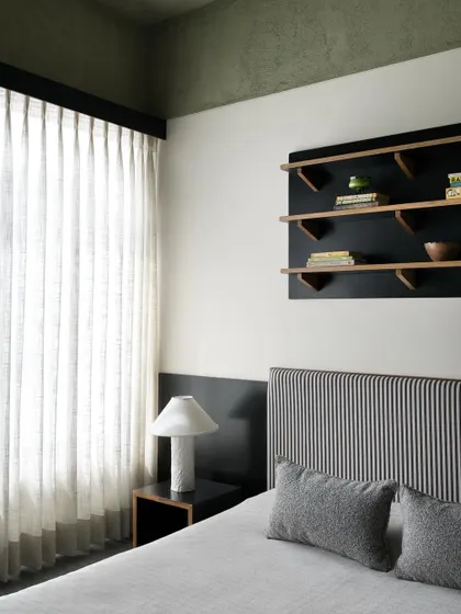 A view of the son's bedroom, showing the striped headboard and custom black bedside table. I design furniture to reflect the user's personality while maintaining a calm and organized environment.