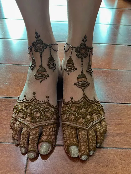 This foot design combines a dense pattern on the toes with a beautiful hanging bell anklet design. It's a perfect blend of full and minimalist styles.