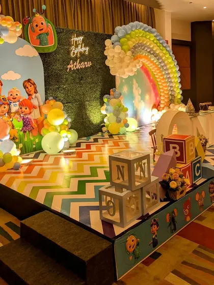 A Cocomelon stage with a chevron-patterned floor and large "ONE" and name marquee letters.