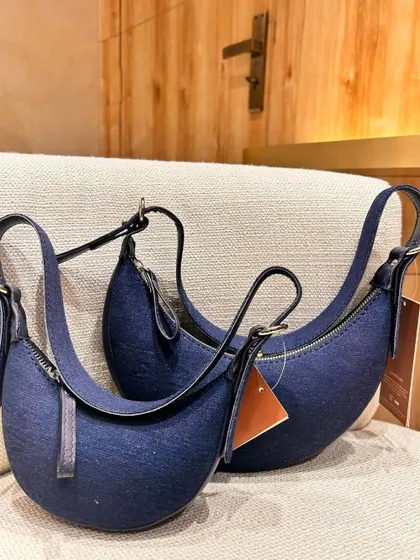 Our bestselling Selena, now in premium denim. This version offers a more casual, everyday feel while retaining the iconic crescent shape and leather details.