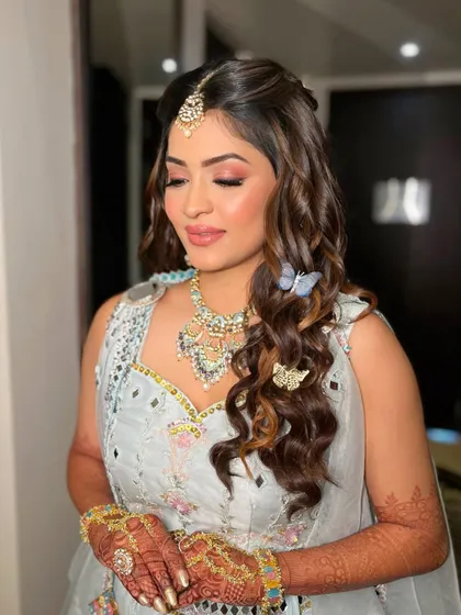 A pink affair for Krisha's haldi. I used soft pink eyeshadow to complement her powder blue outfit, adding whimsical butterfly clips to her hair.