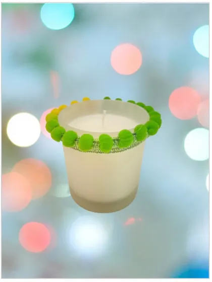 A scented candle in a frosted white glass jar, which I've decorated with a fun, green pom-pom lace. This shows how I can customize candles for a more festive or playful look.