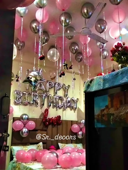 A classic birthday room surprise that never fails to impress. The ceiling is filled with pink and silver balloons with flowing ribbons, paired with 'Happy Birthday' foil letters above the bed for a simple yet joyful celebration.