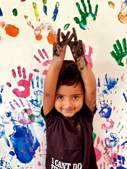 Sometimes learning gets messy, and that's part of the fun! This happy camper is covered in paint after a fun session of handprint art.