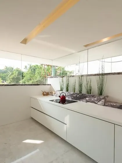 The kitchen in the Neeti Residence. A minimalist design with handleless cabinetry and a large window that opens the space to natural light and views.