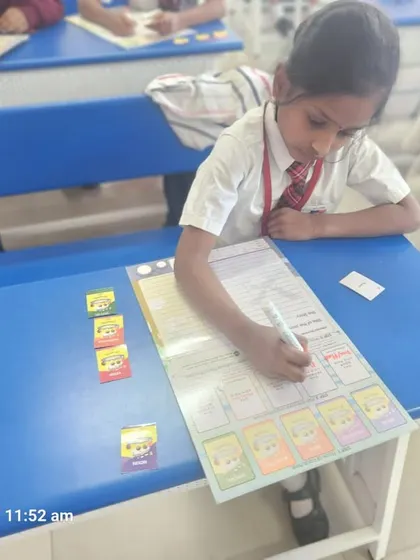 A student carefully places cutouts on her worksheet, an example of the hands-on tasks that help solidify her understanding of the lesson.