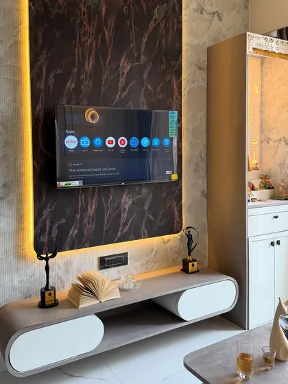 A slightly different angle of the TV and pooja unit combination, showcasing the sleek, modern console table with curved edges and minimalist decor.