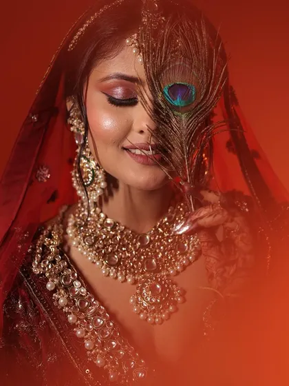A beautiful, artistic portrait using a peacock feather. The colours of the feather complement the warm tones of the makeup.