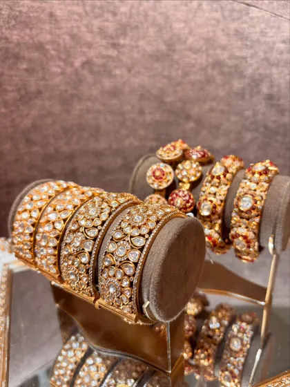 A vision of modern royalty. This image displays a variety of our polki and enamel bangles on stands, reflecting in a mirror.