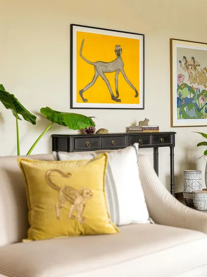 A console table with a pop of yellow art above it. This vignette shows how a simple console can be a great place to display art and personal objects.